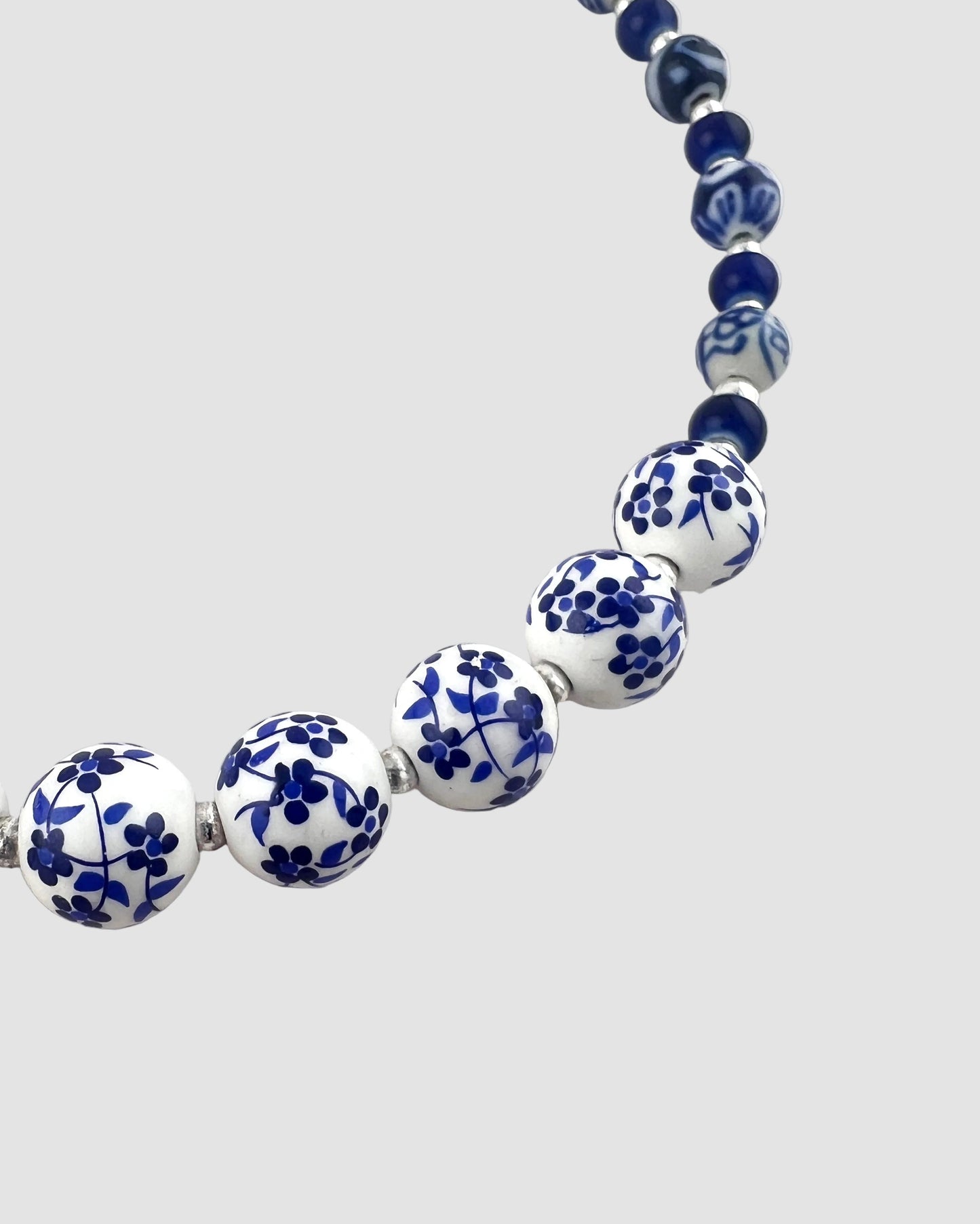Necklace with blue and white floral beads on a light gray background