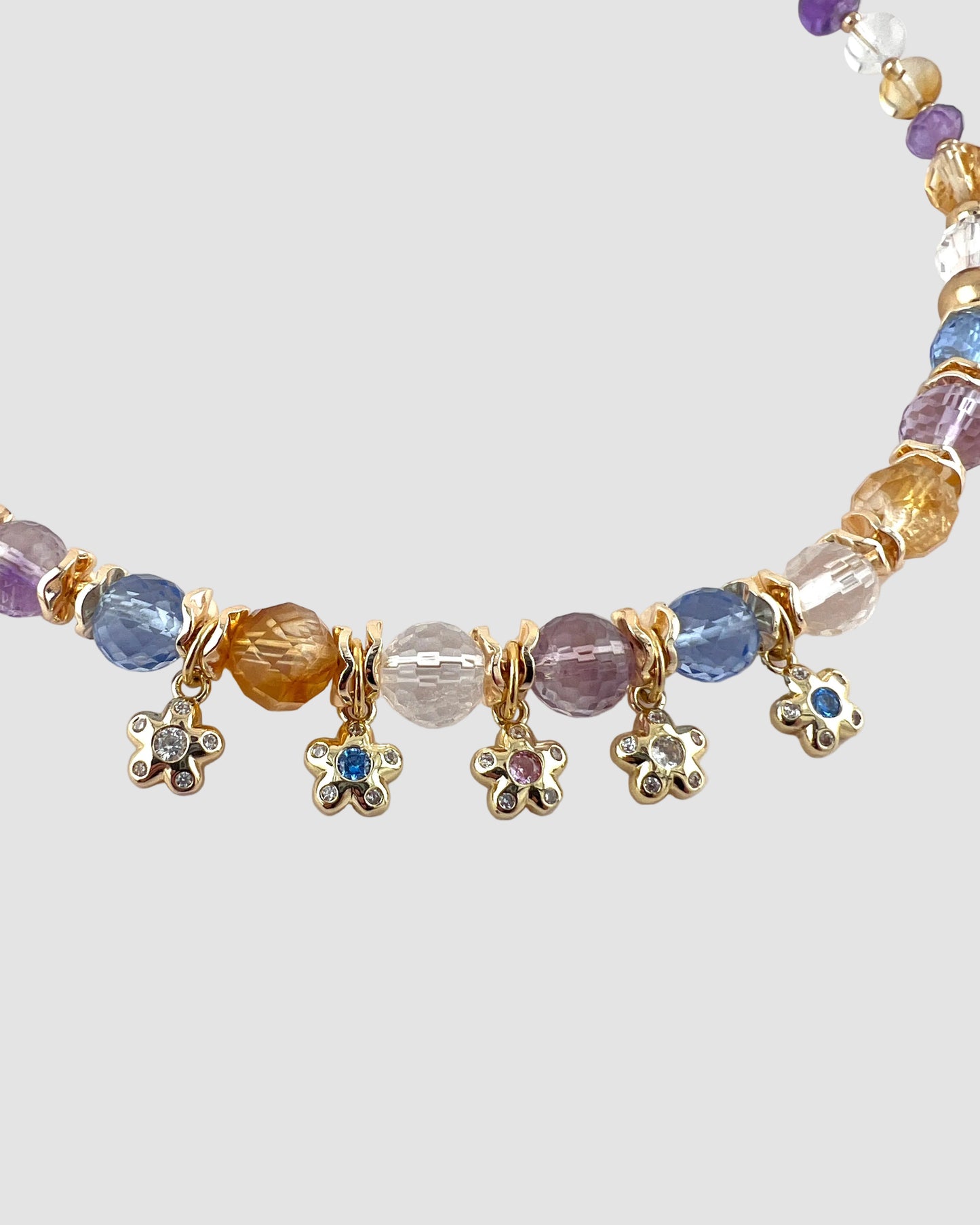 Multicolored beaded necklace with gold charm flowers on a white background
