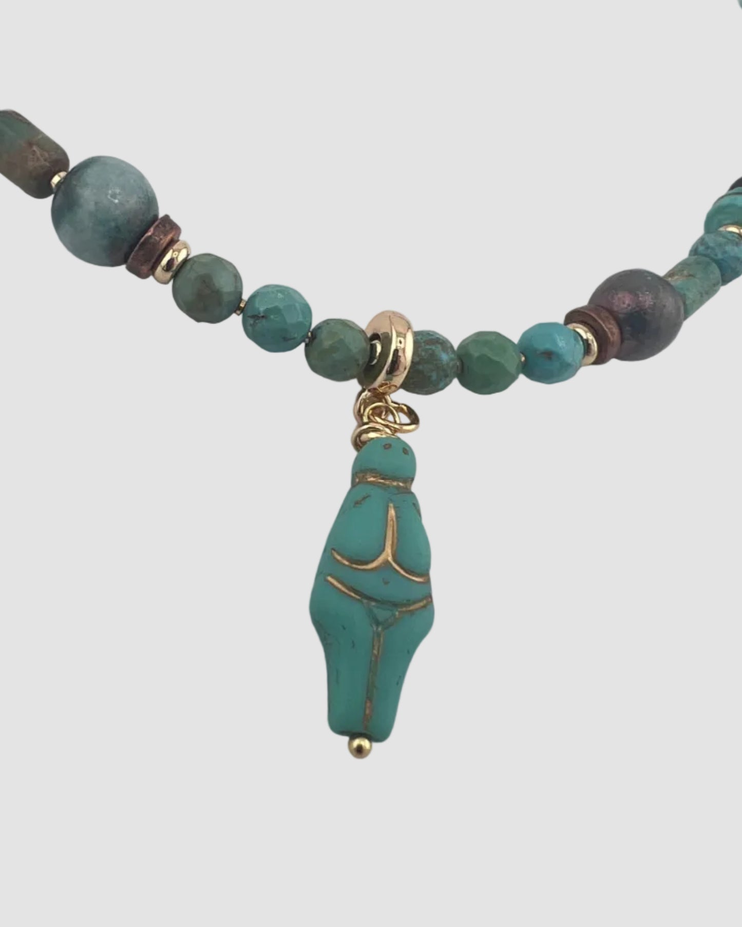 Necklace with turquoise beads and a decorative pendant on a light gray background