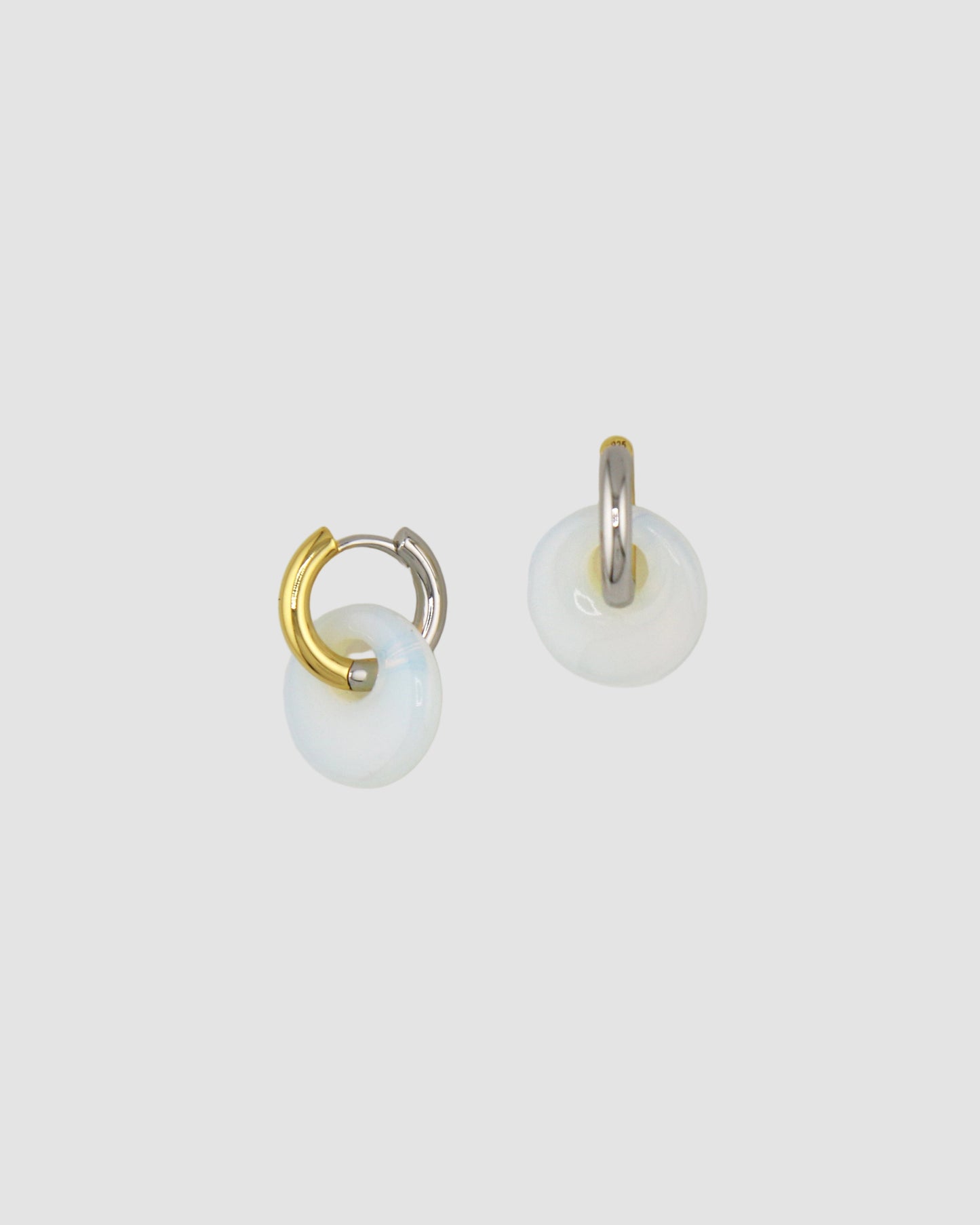 Pair of gold and silver hoop earrings on a light gray background