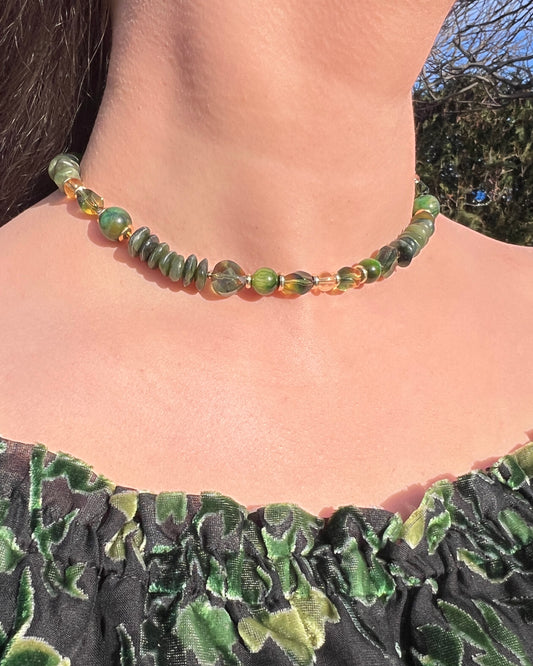 Green beaded necklace worn by a person with a blurred natural background