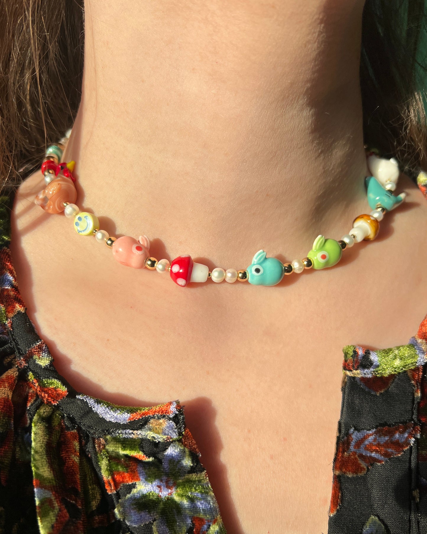Colorful beaded necklace worn by a person with a floral dress.