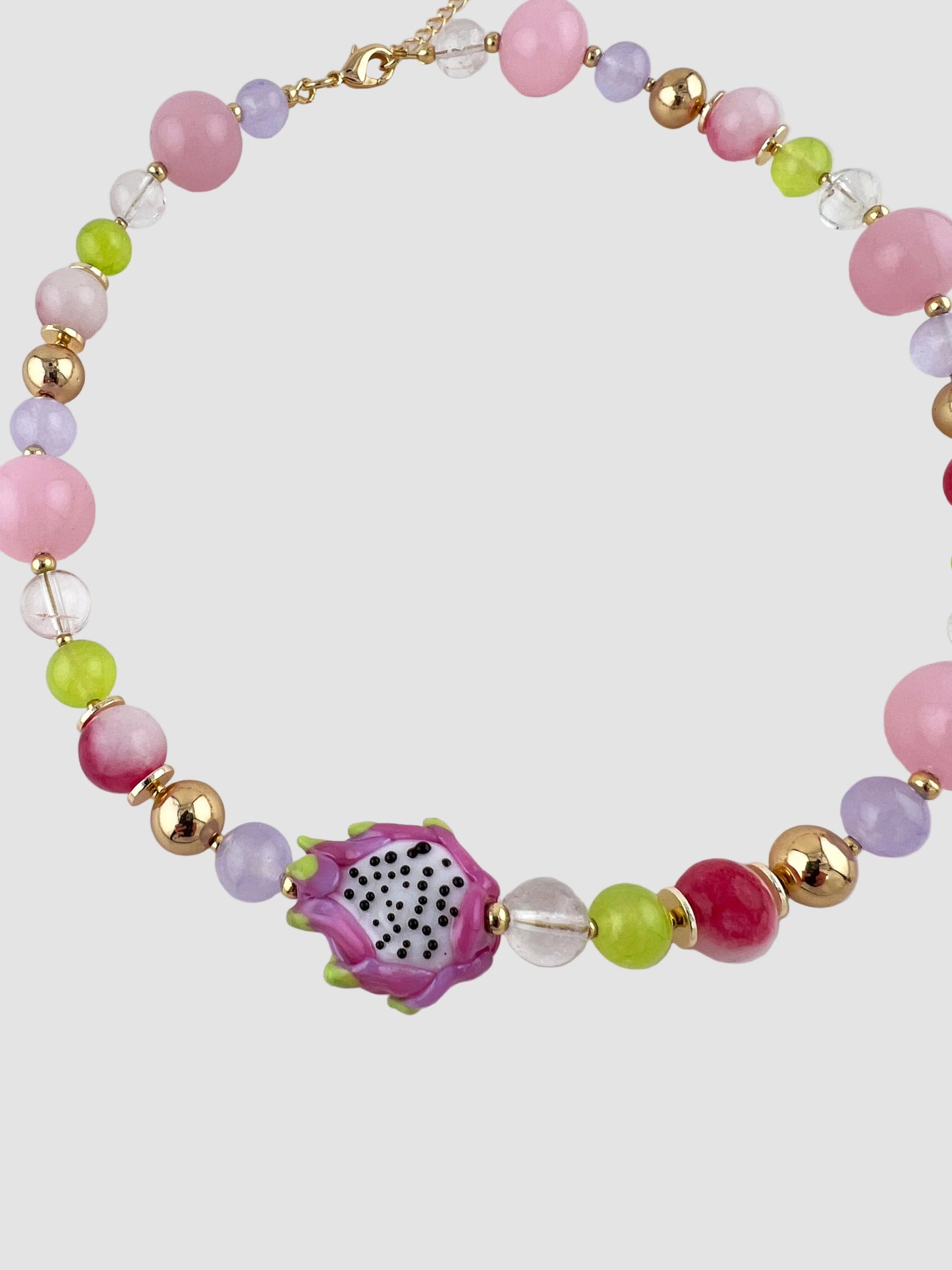 Colorful beaded necklace with a dragon fruit-shaped charm on a white background