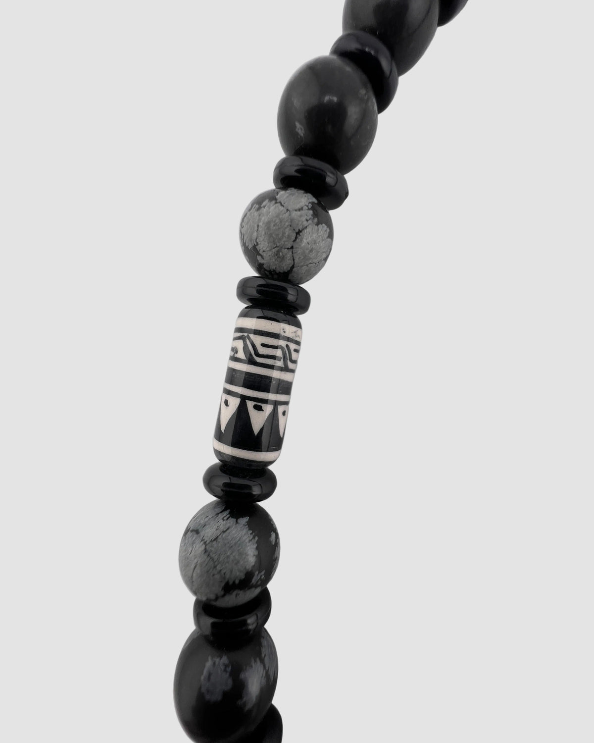 Black beaded necklace with a patterned focal bead on a white background