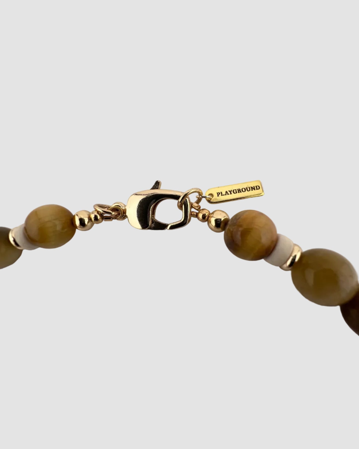 Necklace with gold clasp and tieger's eyebeads on a light gray background