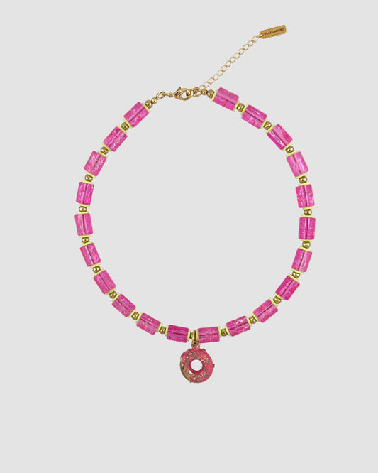 Necklace with pink beads and a pink donut charm on a light gray background