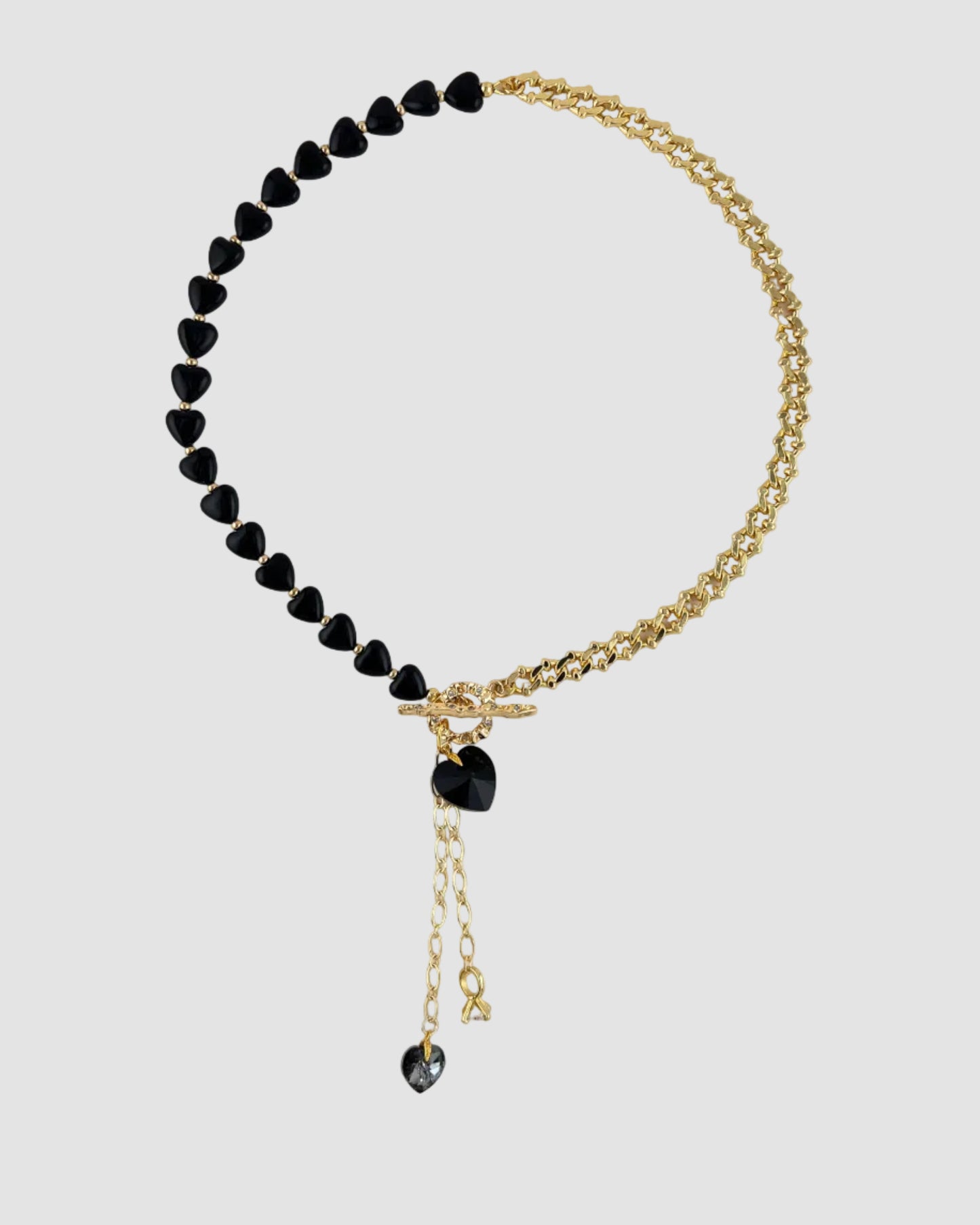 Necklace with black heart-shaped beads and a gold chain on a white background