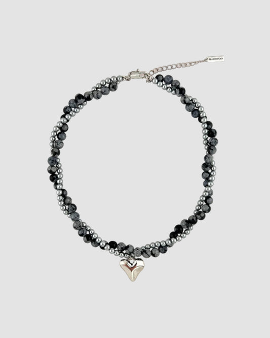 Beaded necklace with a silver heart charm on a white background