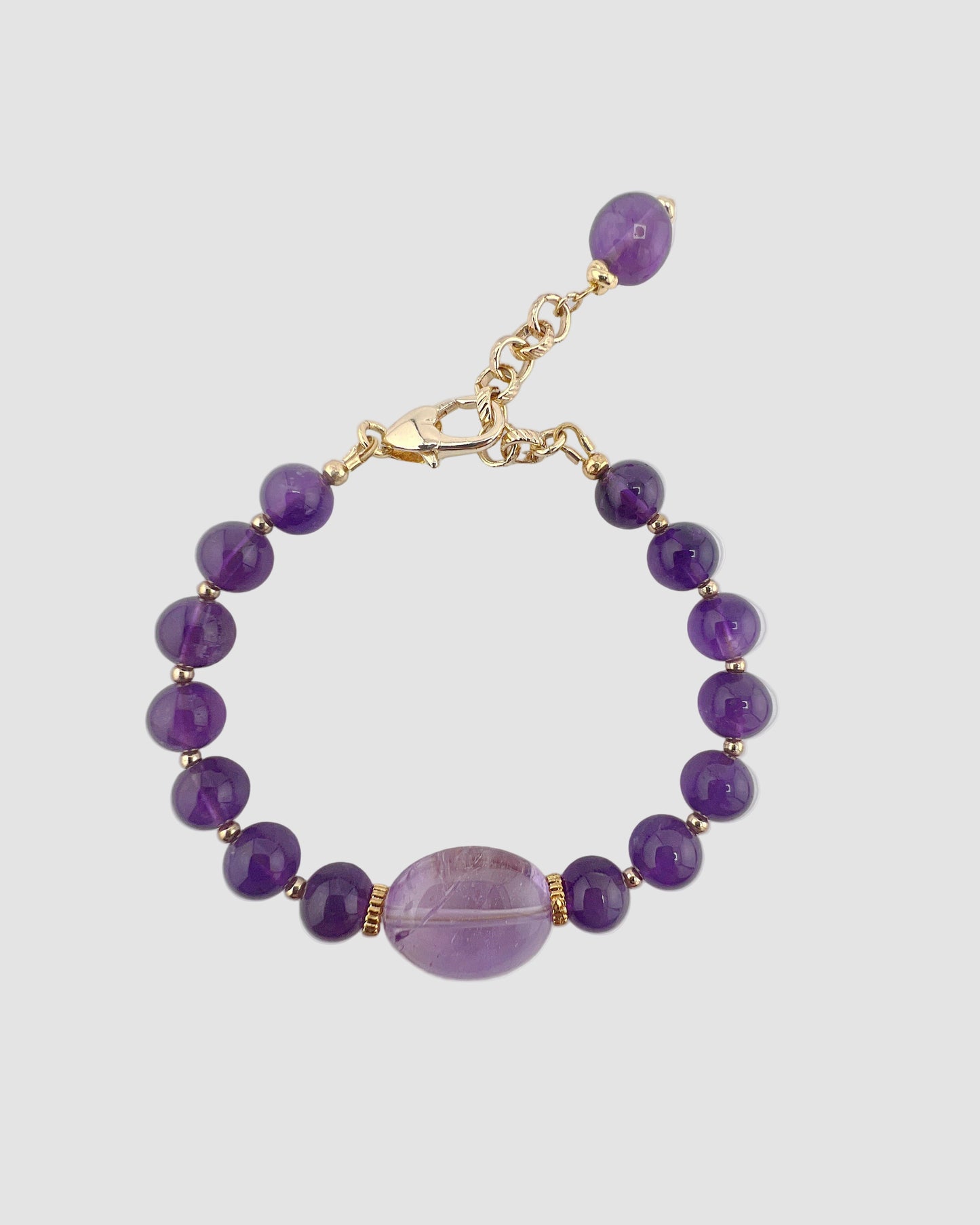 Purple beaded bracelet with a gold clasp on a gray background