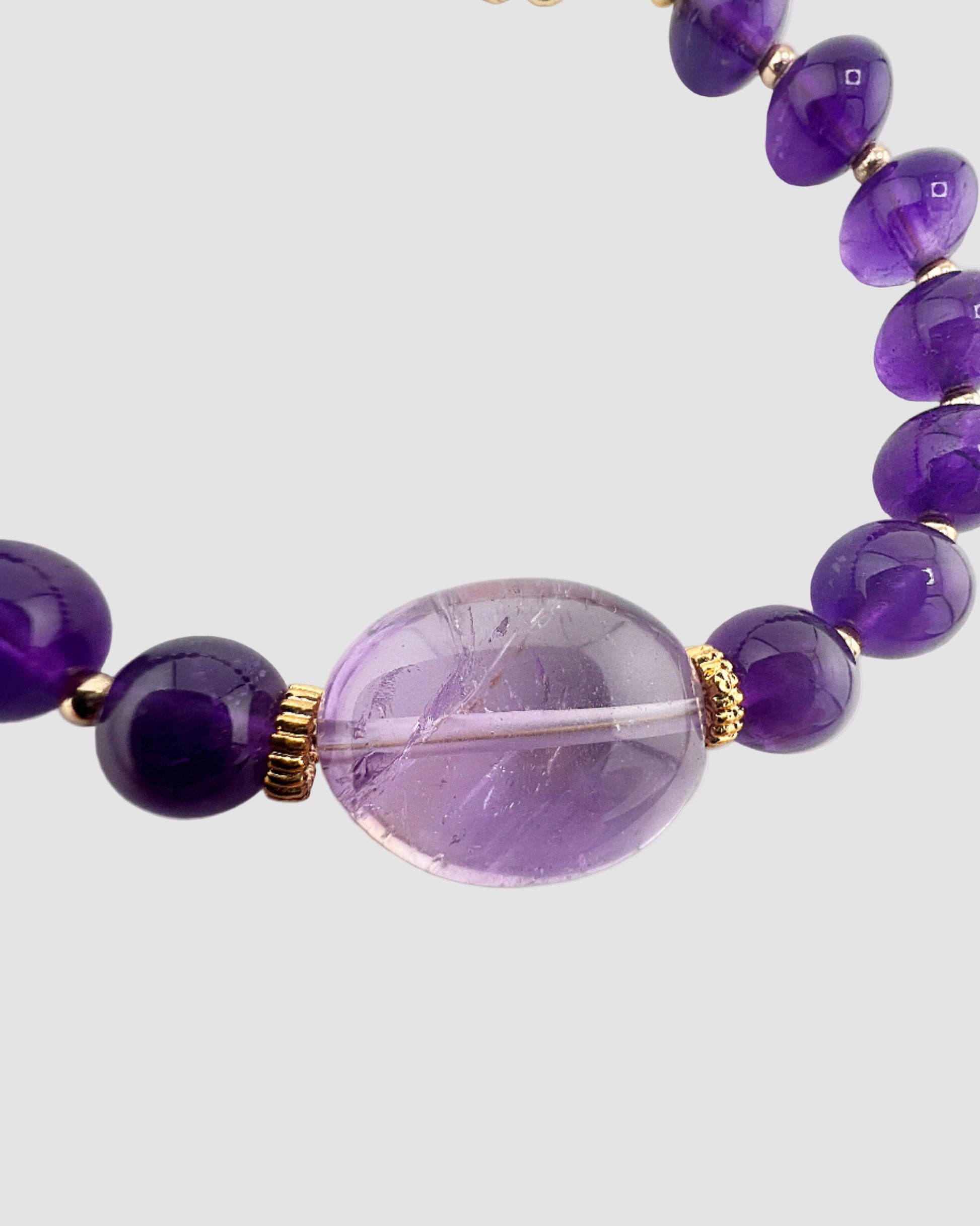 Bracelet with purple beads and a clear central bead on a white background
