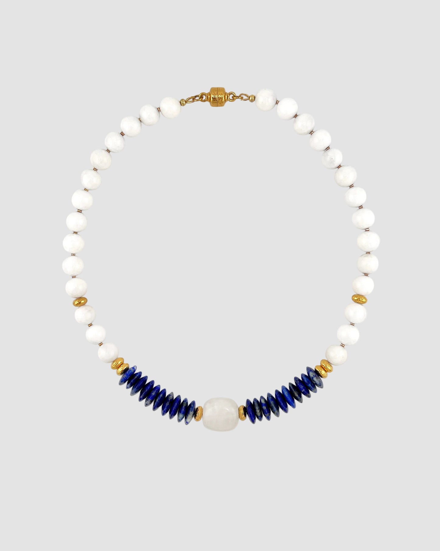 Necklace with white beads and blue accents on a light gray background