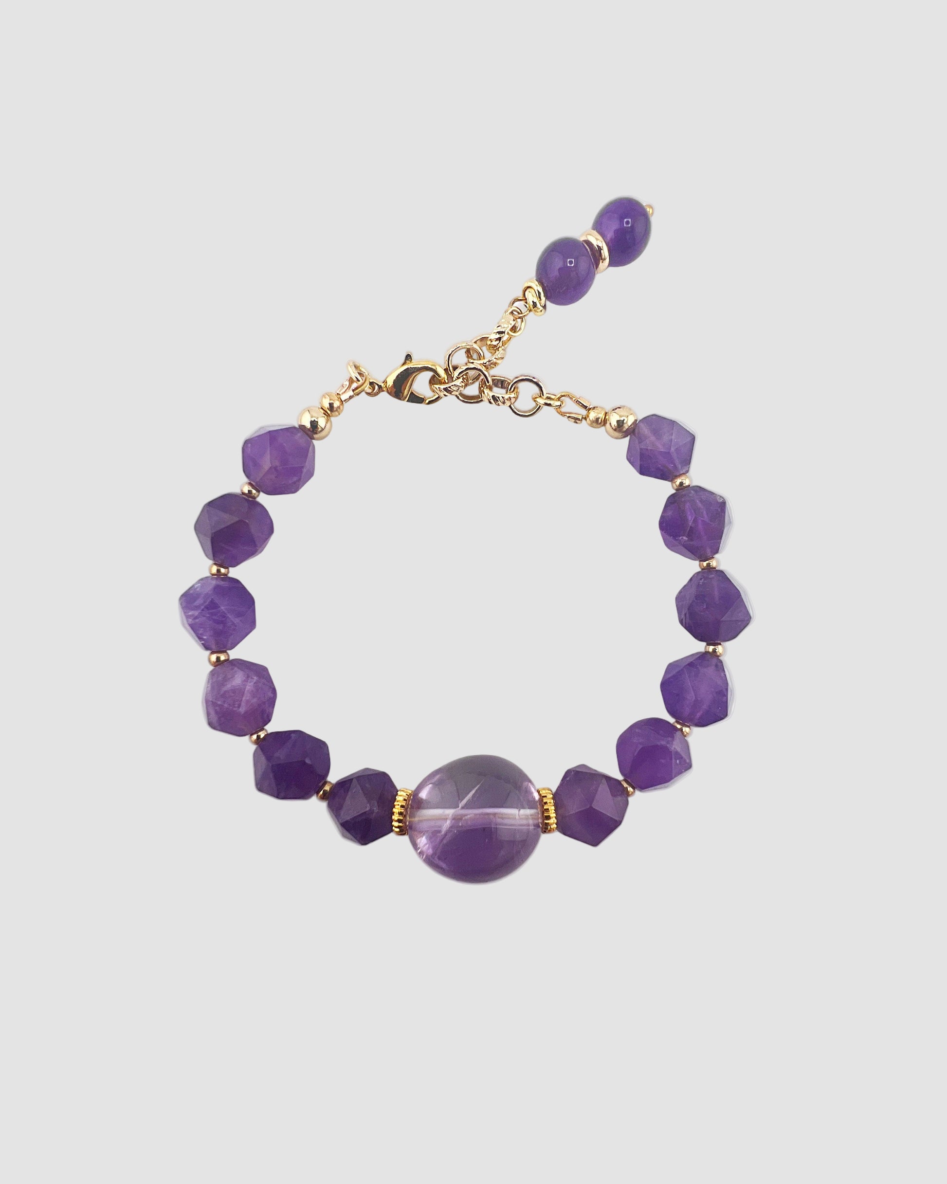 Purple beaded bracelet with gold accents on a light gray background