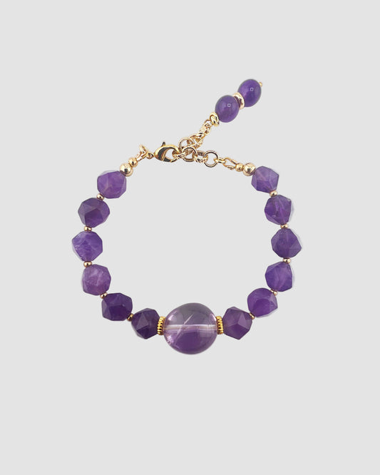 Purple beaded bracelet with gold accents on a light gray background