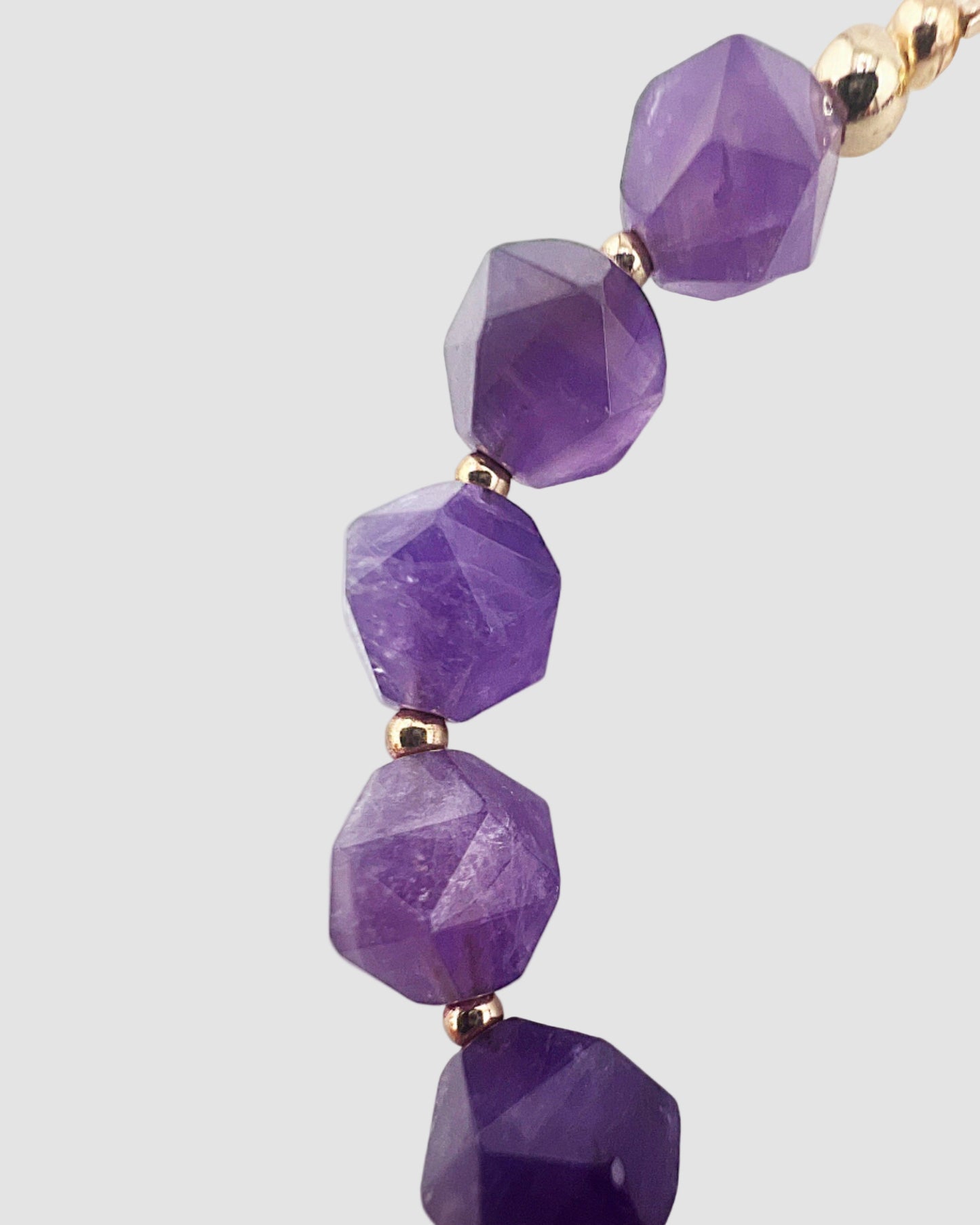 Purple beaded bracelet with gold accents on a white background