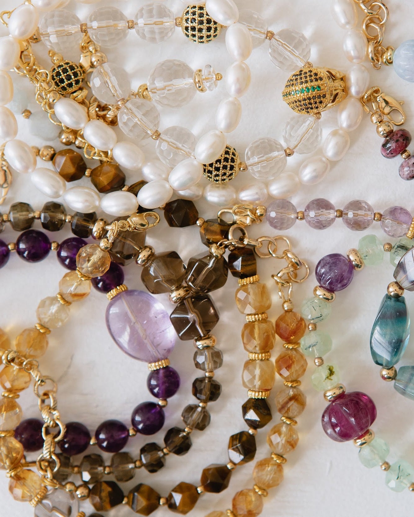 Collection of beaded necklaces with various colors and designs on a white background