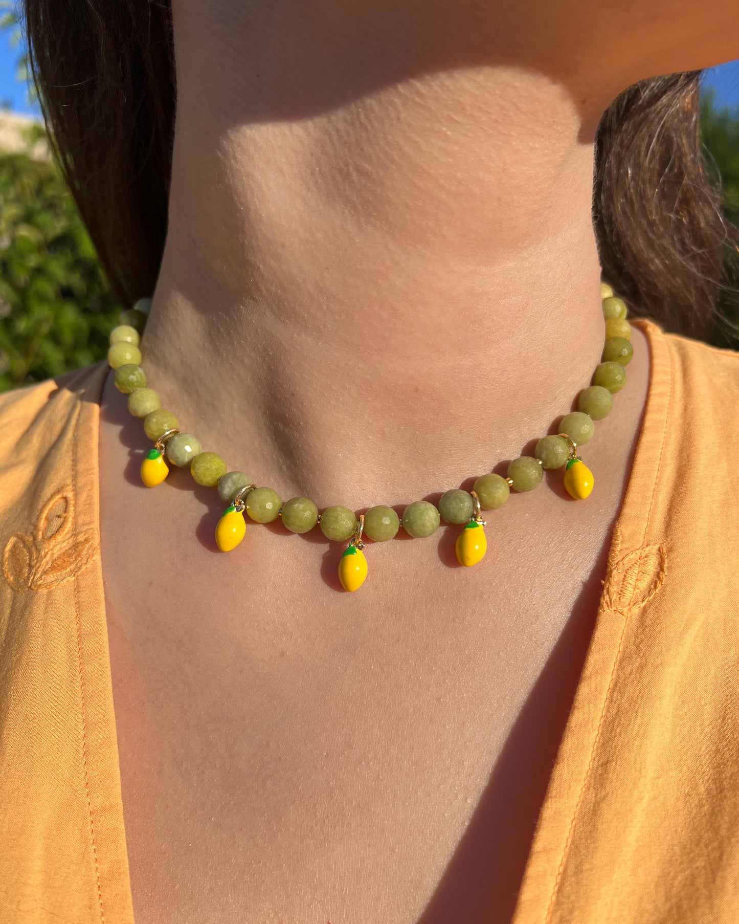 Close-up of a green beaded necklace on a neck with a blurred background