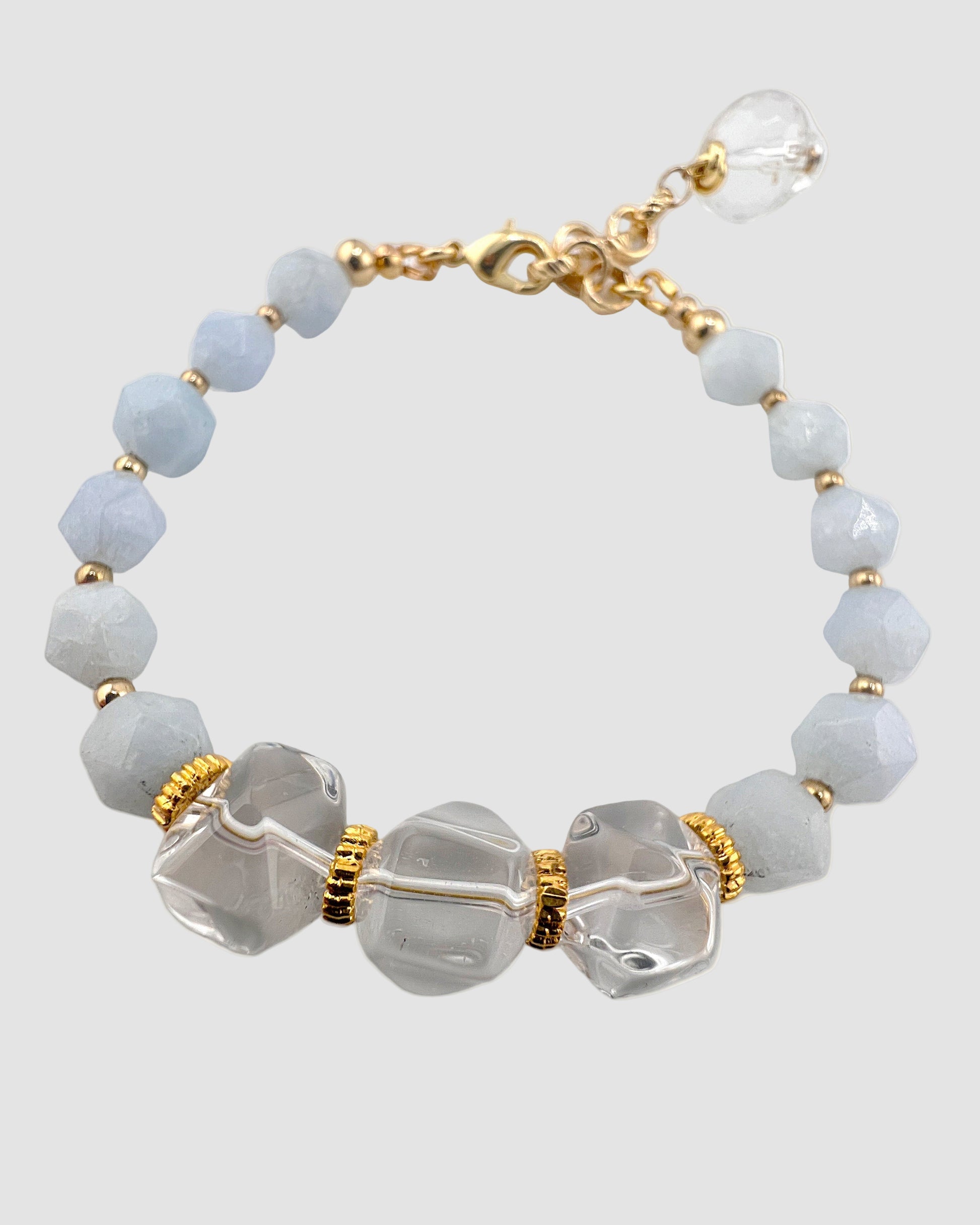 Bracelet with light blue beads, clear crystals, and gold accents on a white background