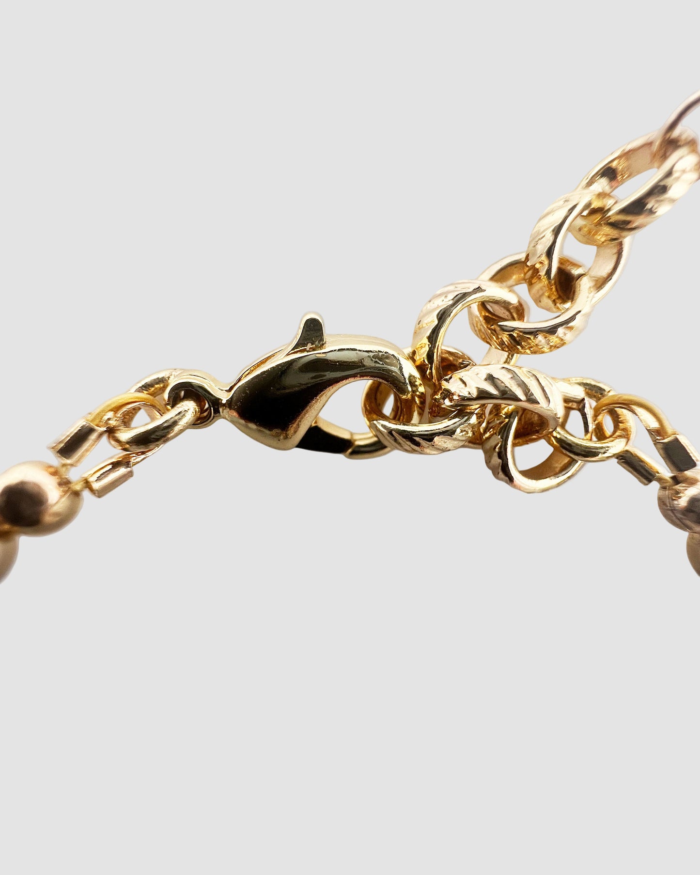 Close-up of a gold-plated lob bracelet on a light gray background