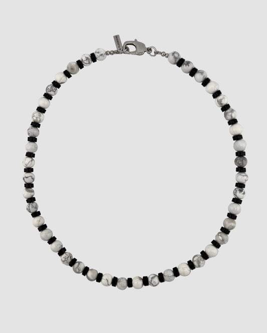 Beaded men's necklace with black, white, and gray beads on a light gray background