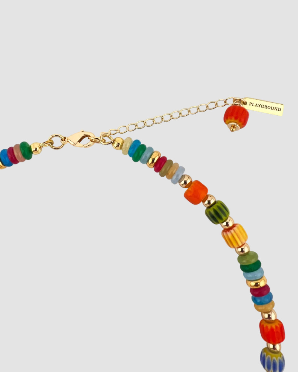 A colorful beaded chain necklace with gold-tone hardware, featuring a lobster clasp, extension chain, and a small gold tag engraved with 'PLAYGROUND'. The beads are multicolored with gold spacer accents.
