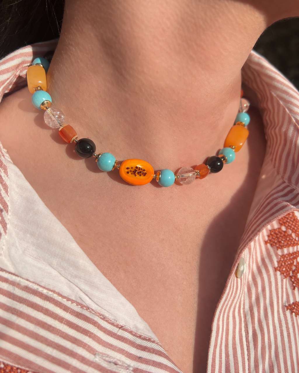 Colorful beaded necklace worn by a person with a striped shirt