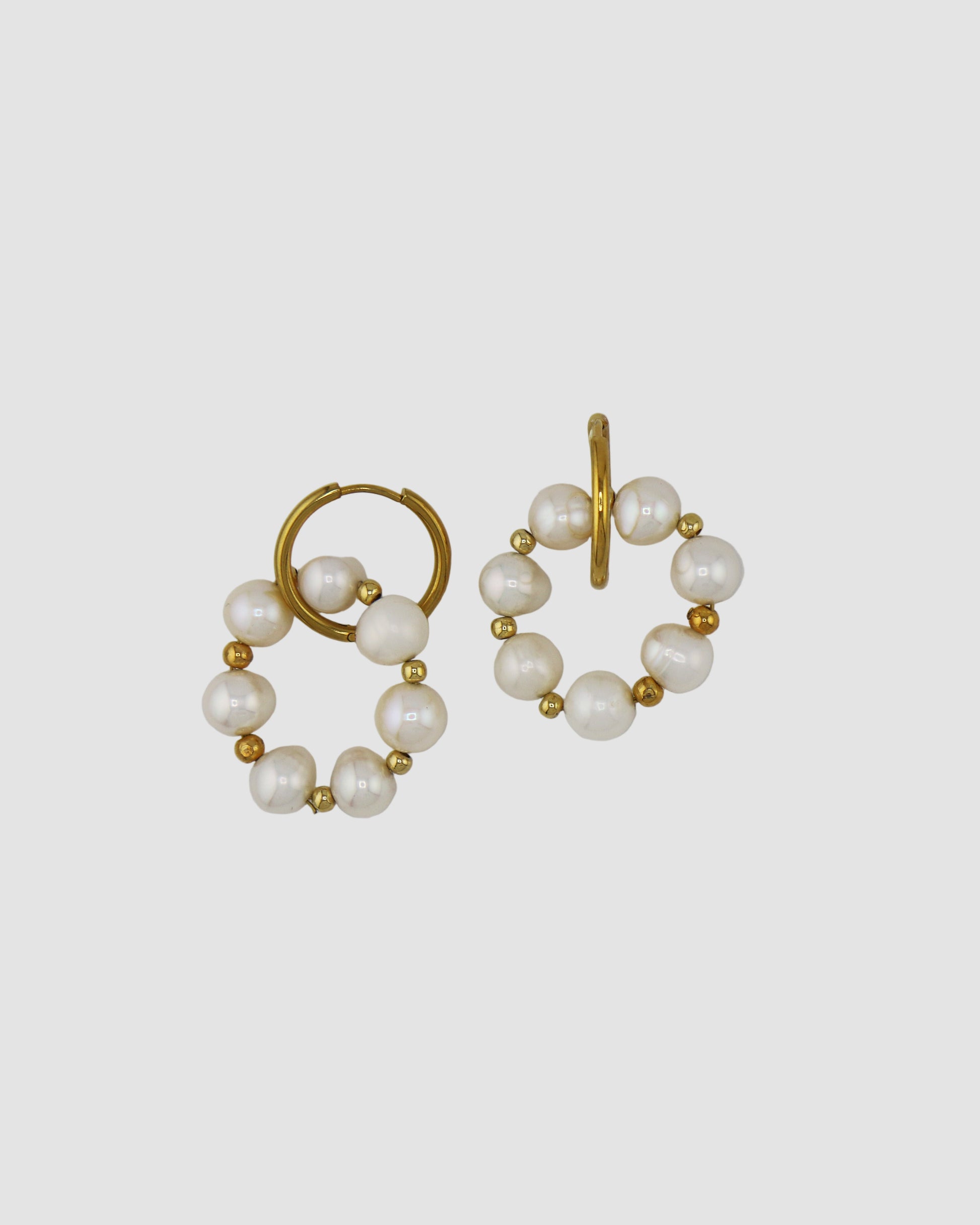 Pair of pearl and gold hoop earrings on a light gray background