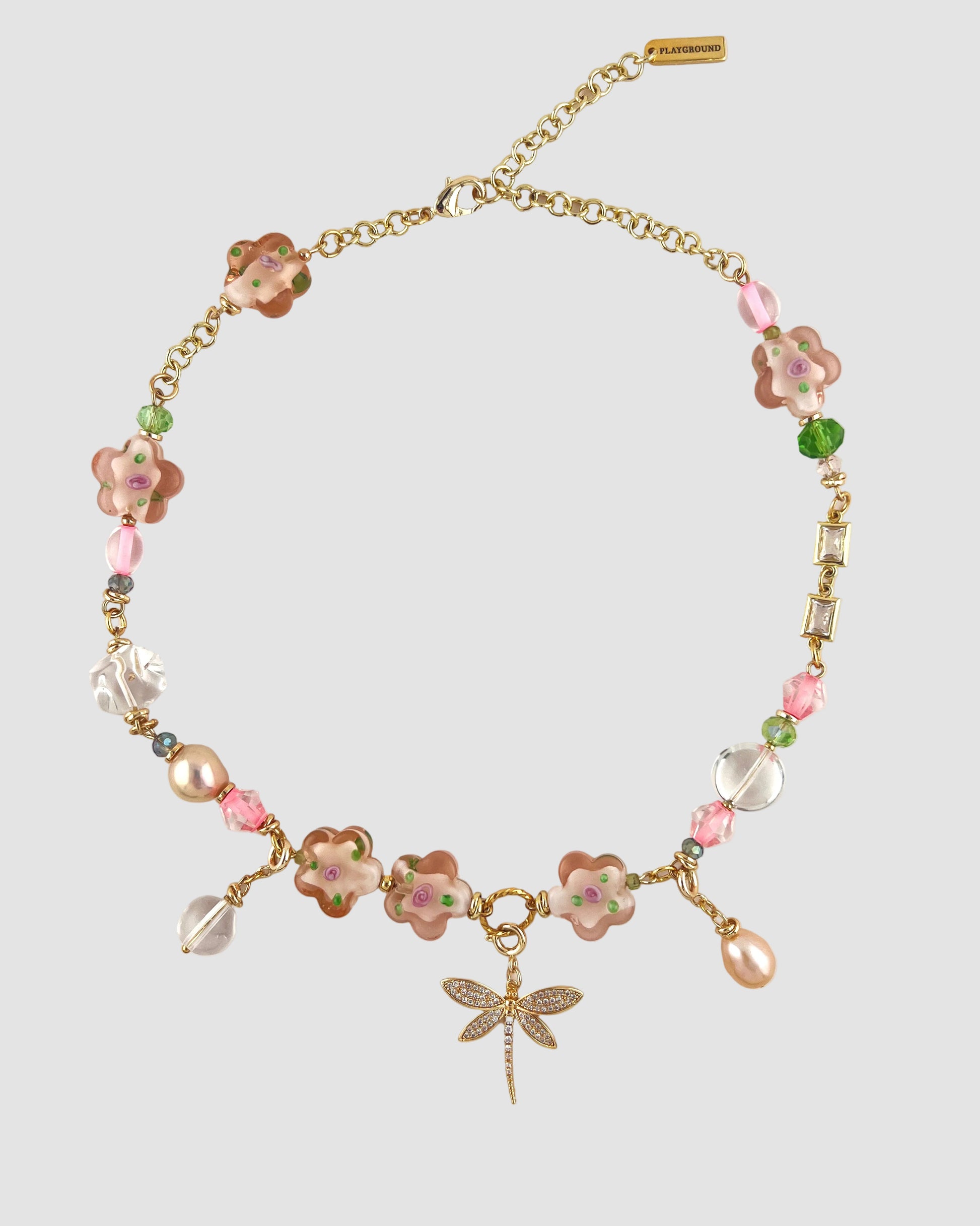Necklace with floral beads and a dragonfly charm on a white background