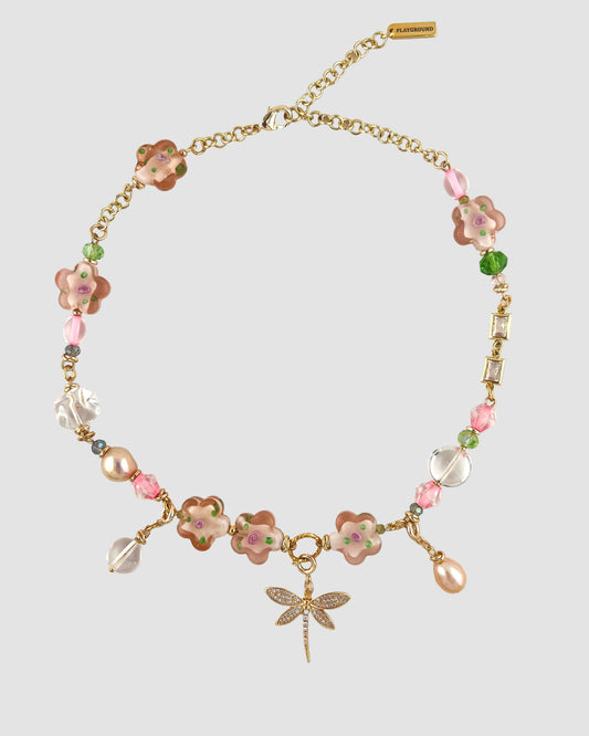 Necklace with floral beads and a dragonfly charm on a white background