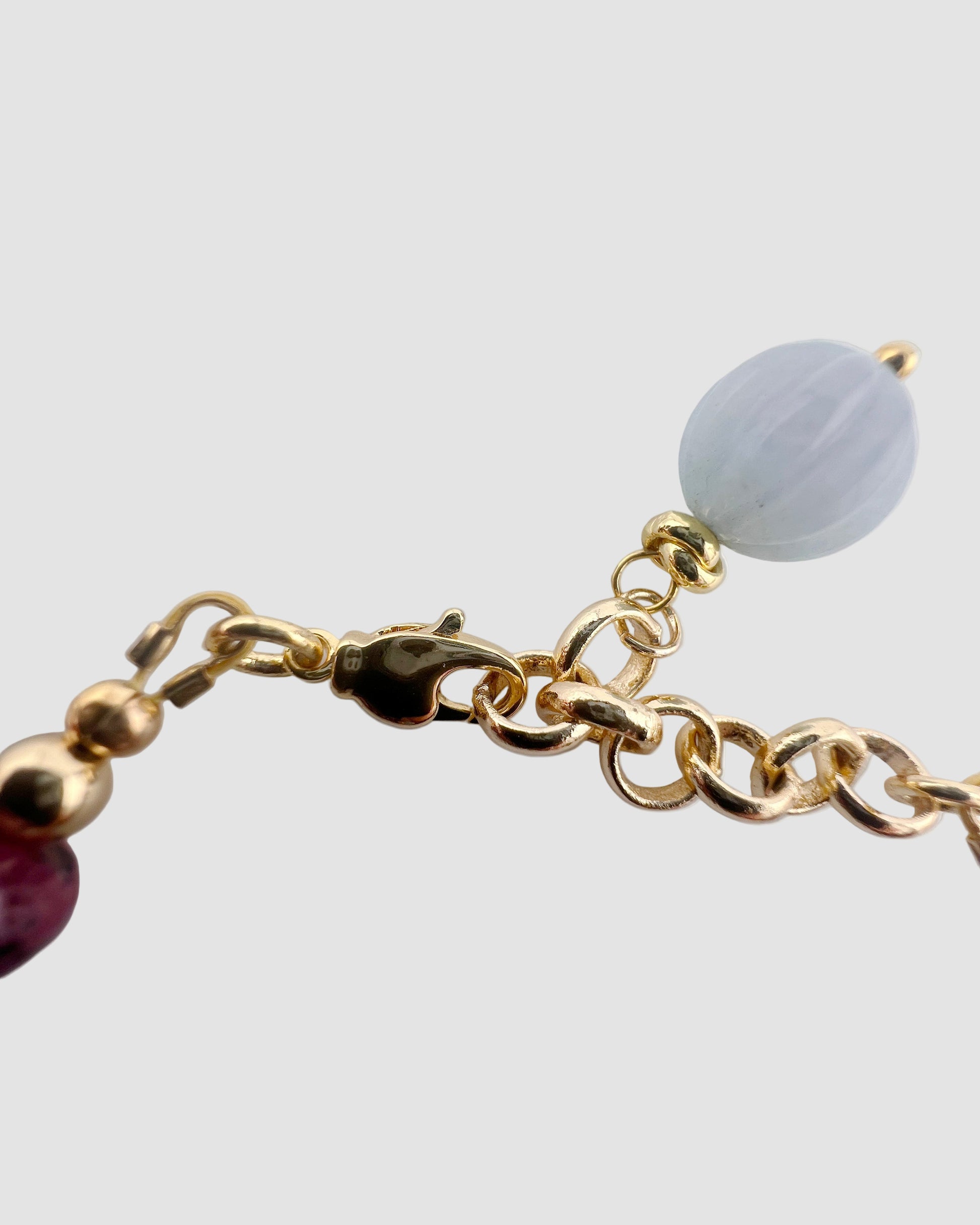 Quartz bracelet with gold lobster clasp on a light gray background