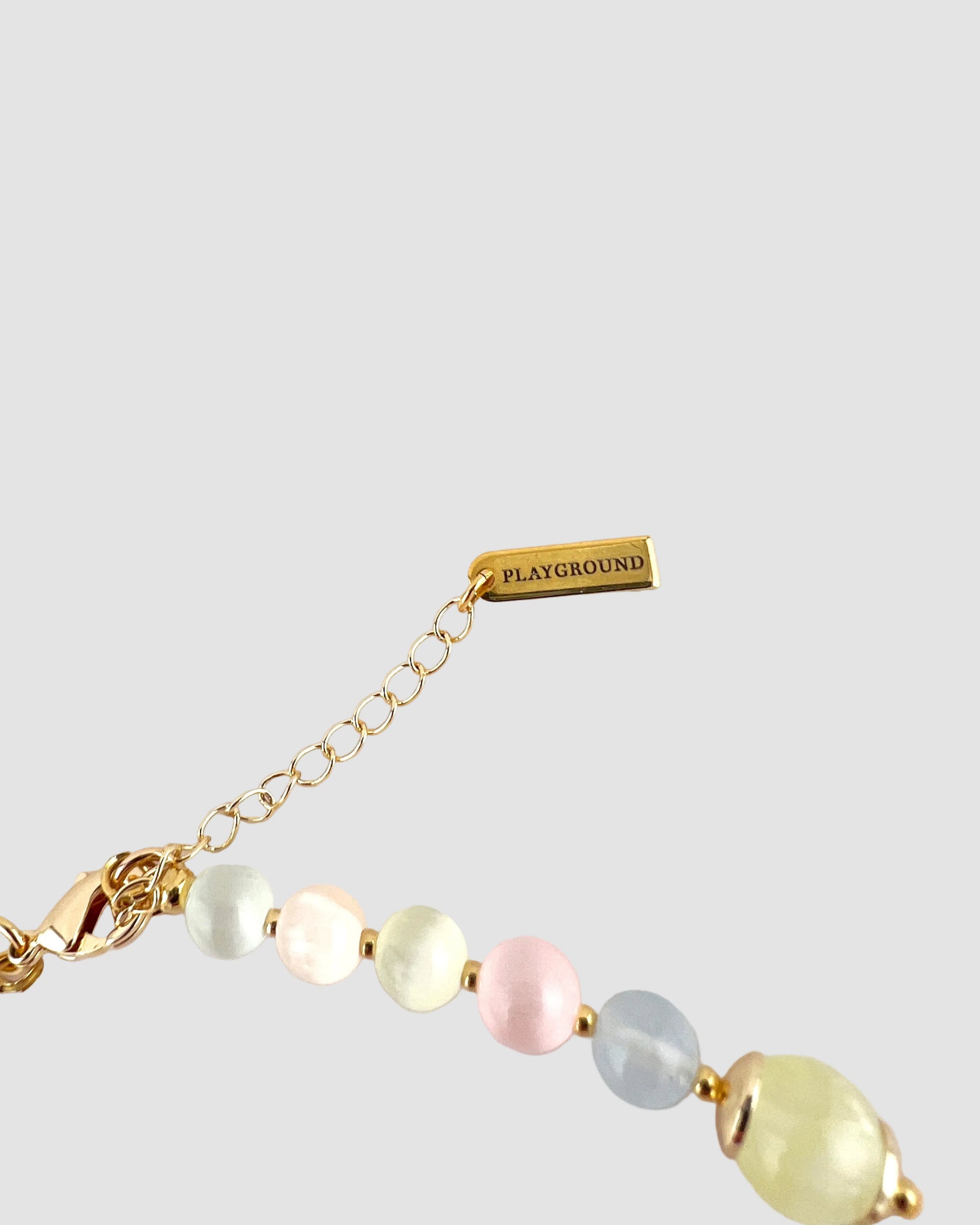 Necklace with pastel beads and gold chain on a white background, featuring 'Playground' brand.