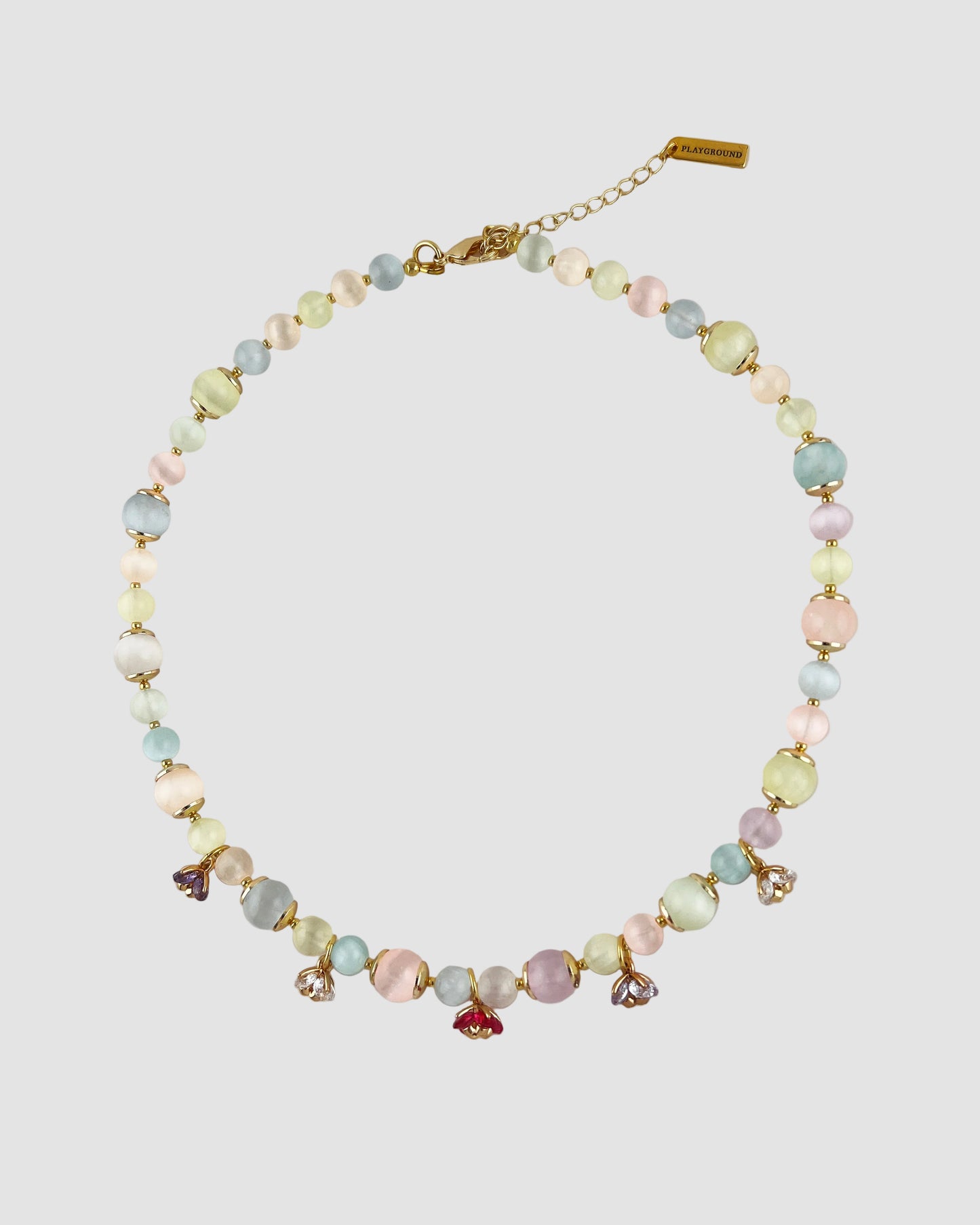 Necklace with pastel beads and small charms on a light gray background