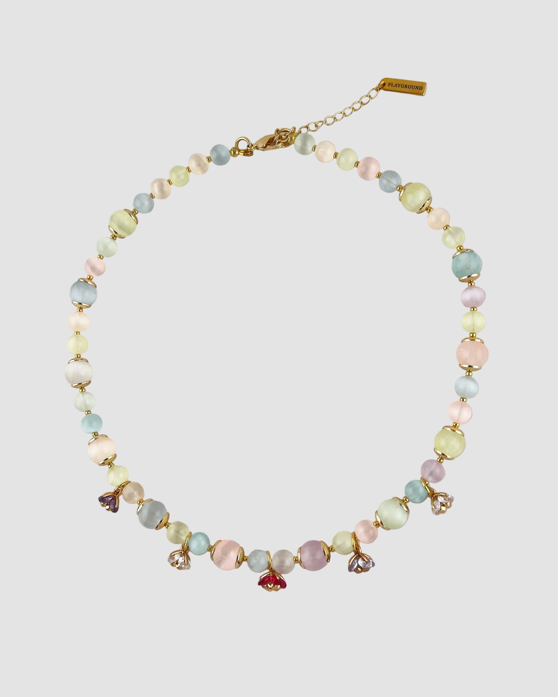 Necklace with pastel beads and small charms on a light gray background