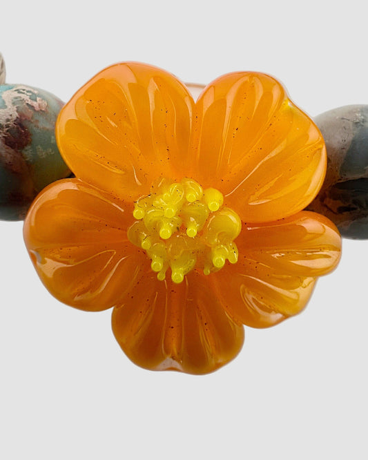 Necklace with a large orange flower bead and smaller beads on a white background