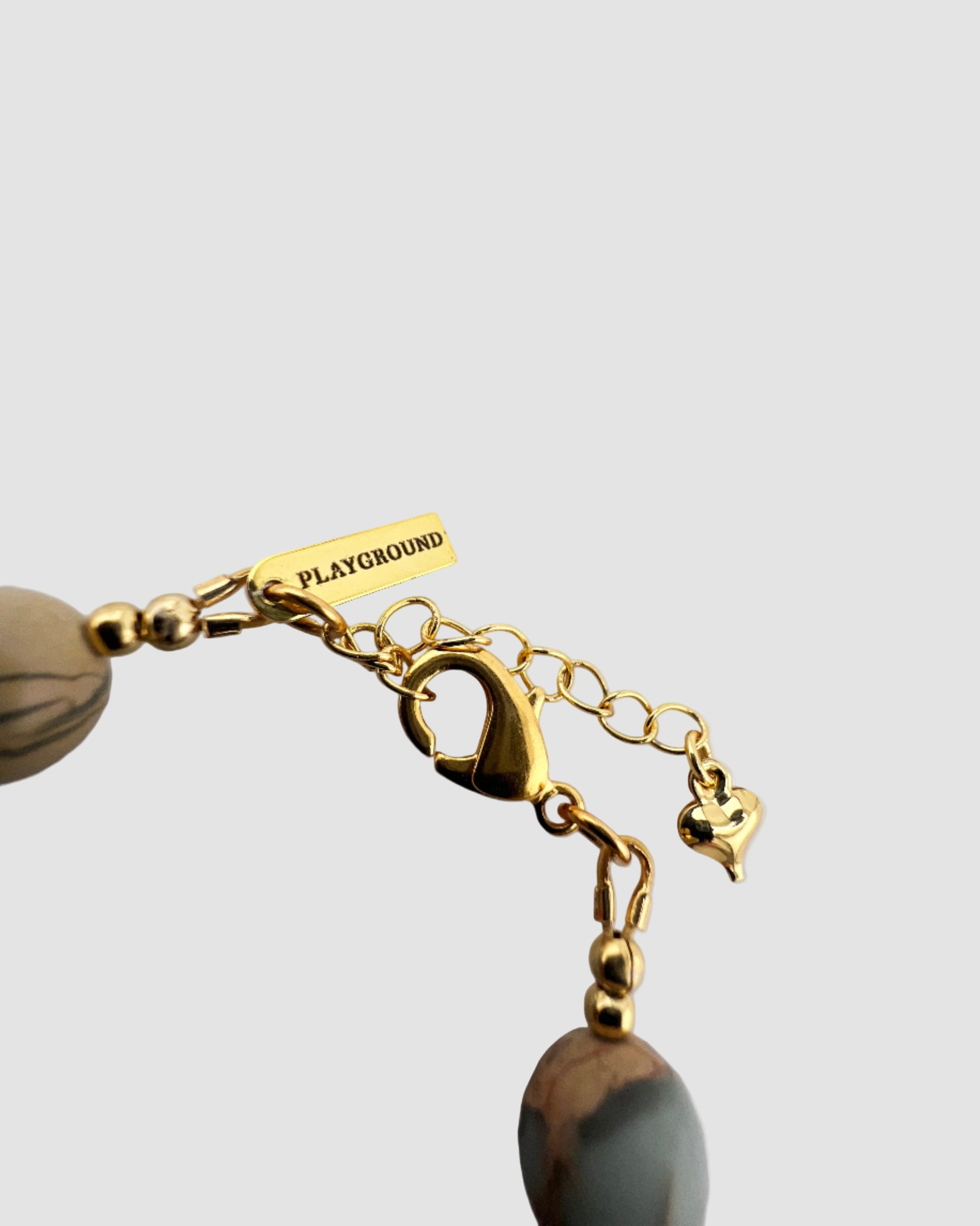 Gold-plated bracelet with a 'Playground' tag on a light gray background