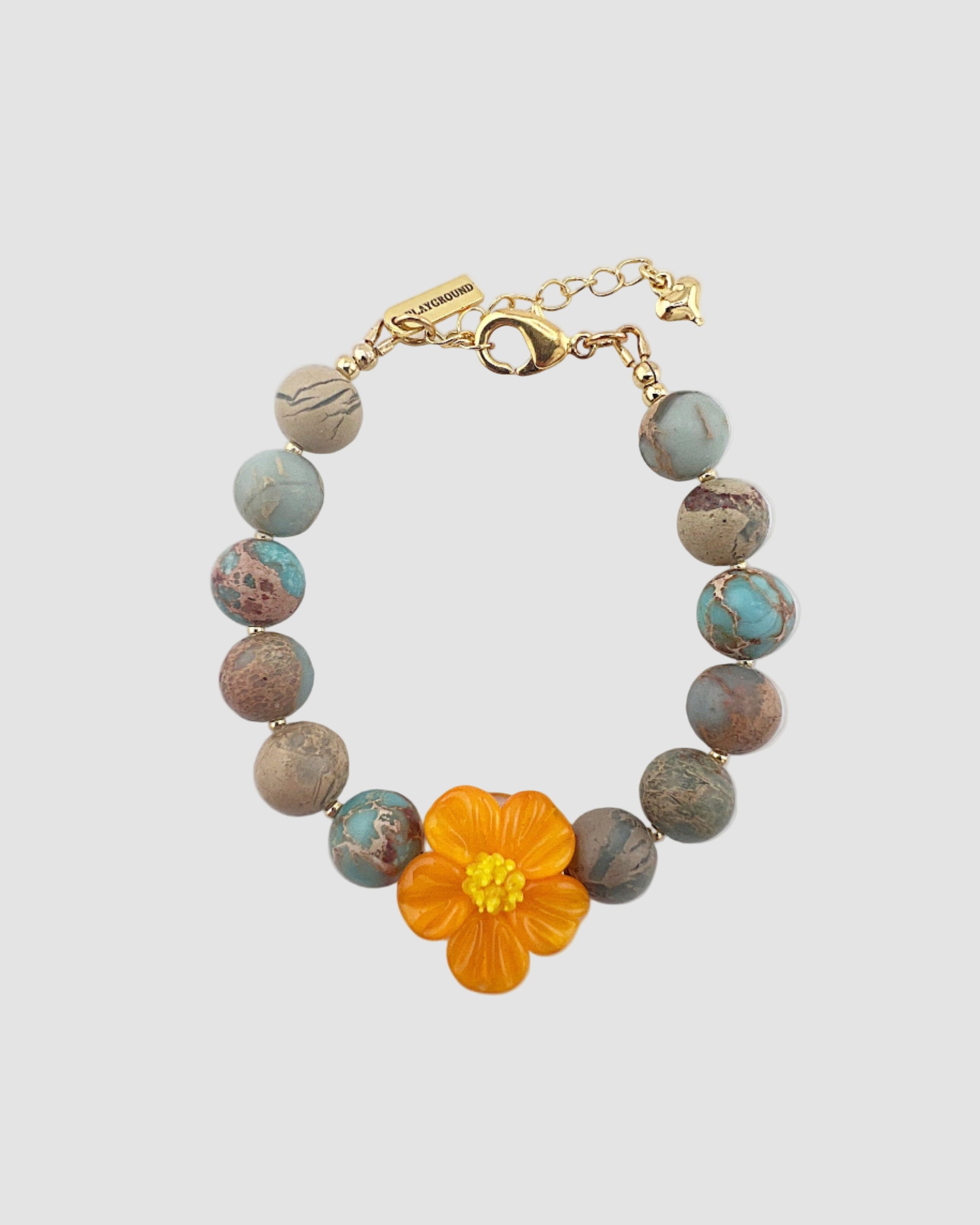 Bracelet with an orange flower charm on a light gray background