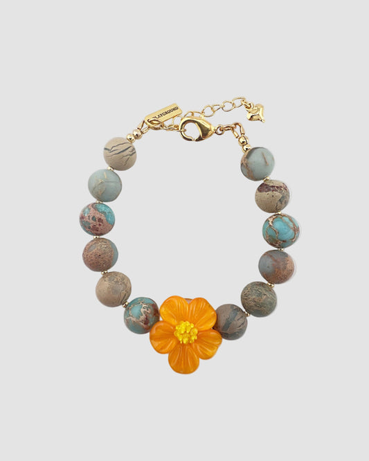 Bracelet with an orange flower charm on a light gray background