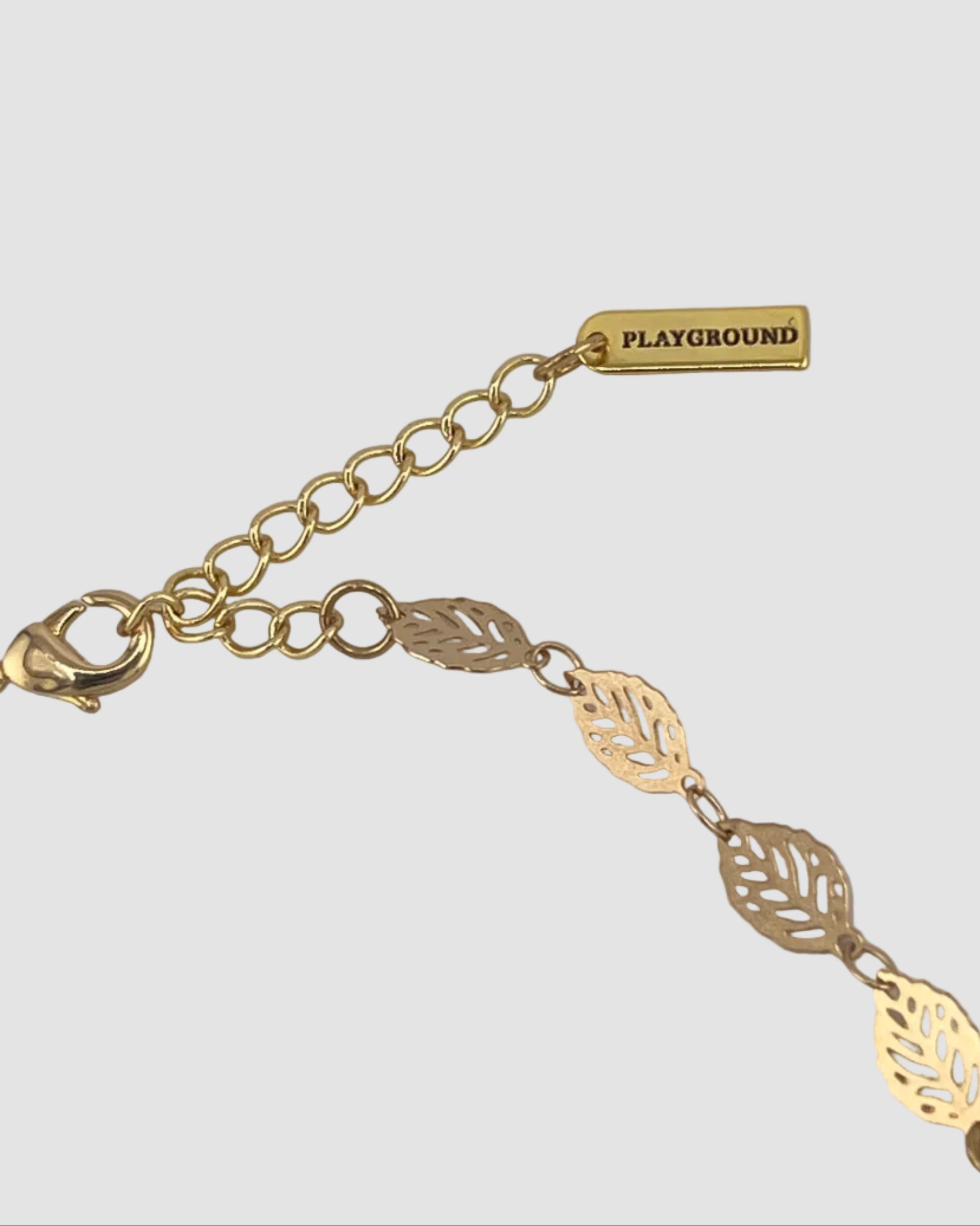 Gold necklace with leaf designs on a gray background