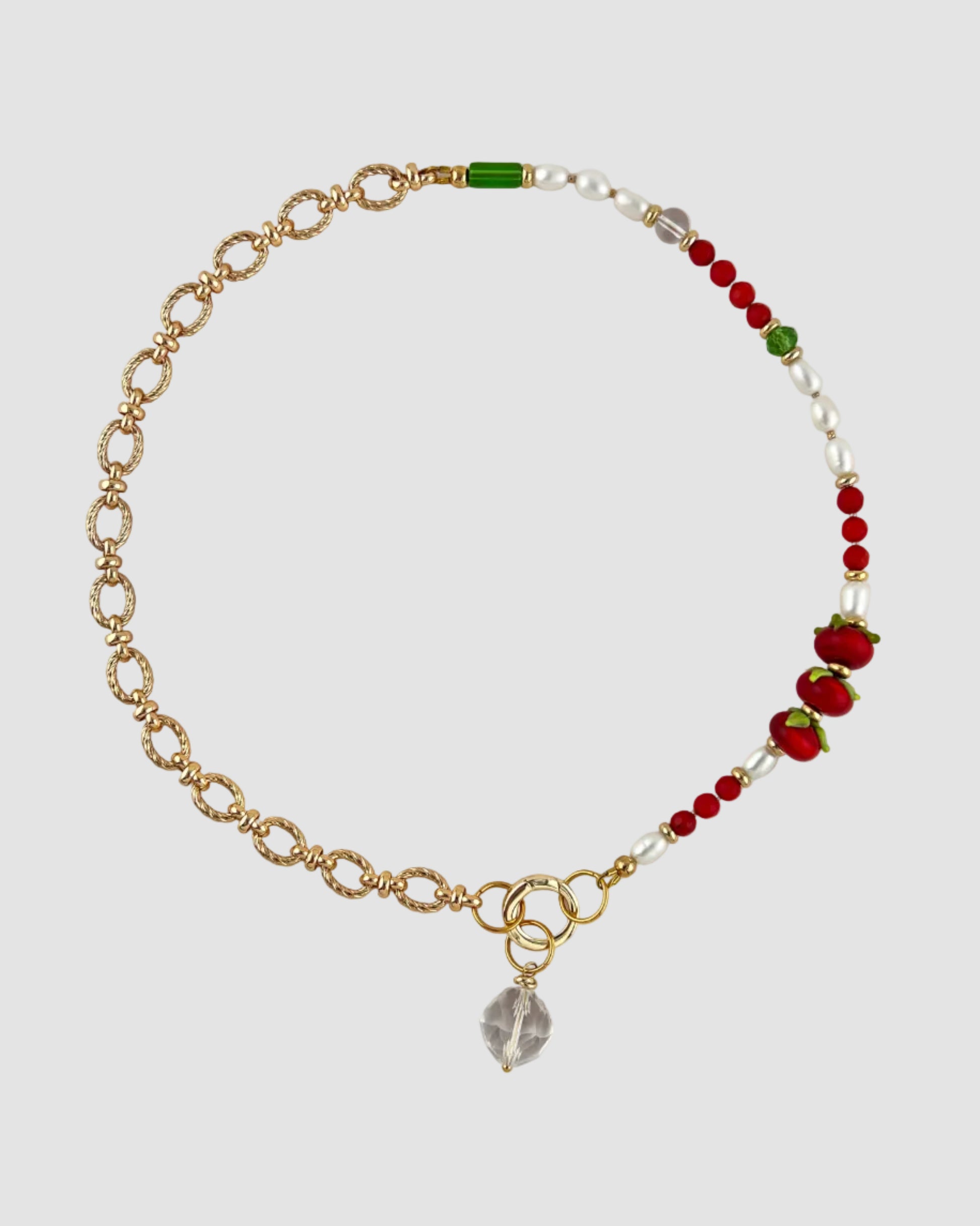 Nacklace with gold chain, red and green beads on a light gray background