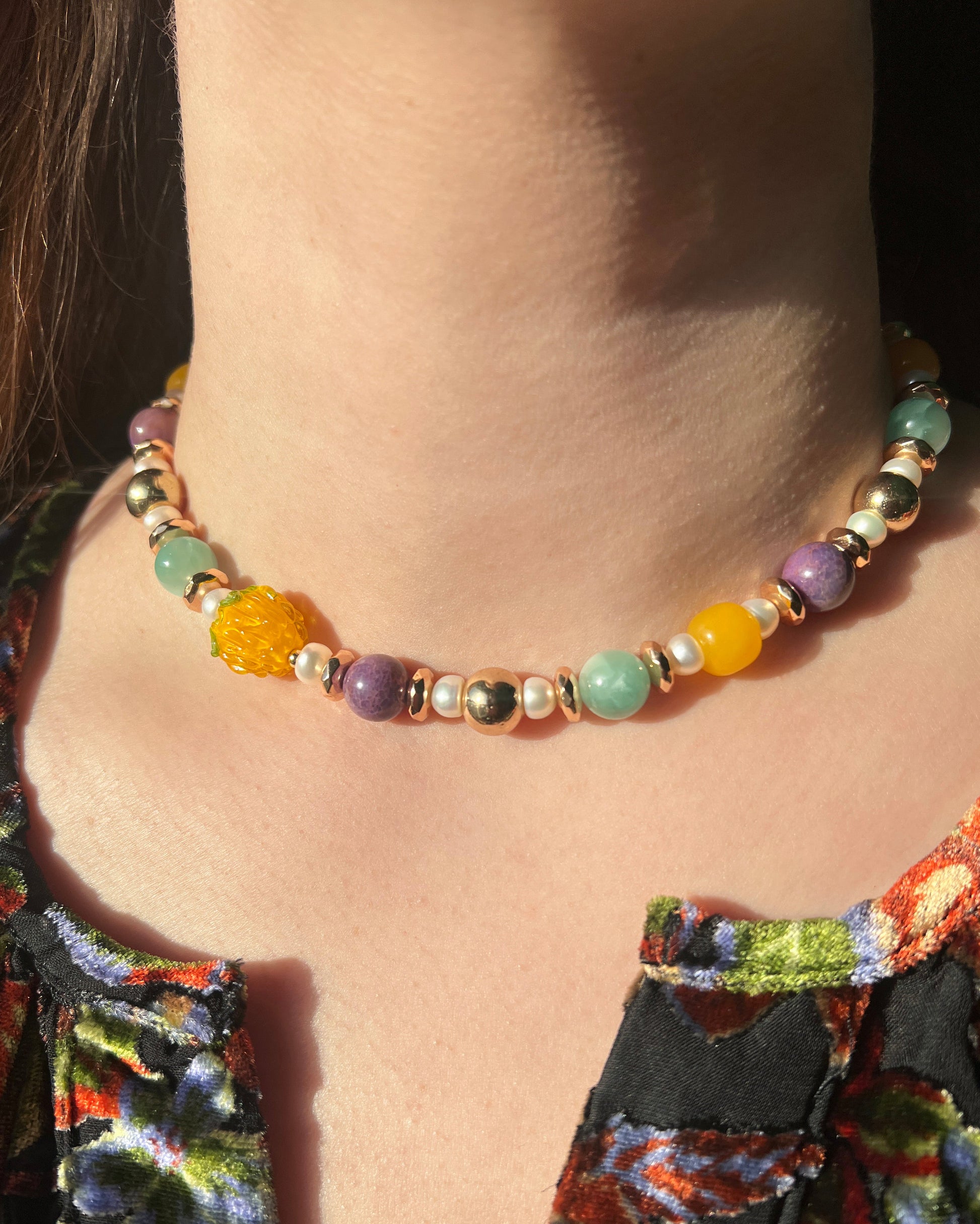 Colorful beaded necklace worn by a person with a patterned top.